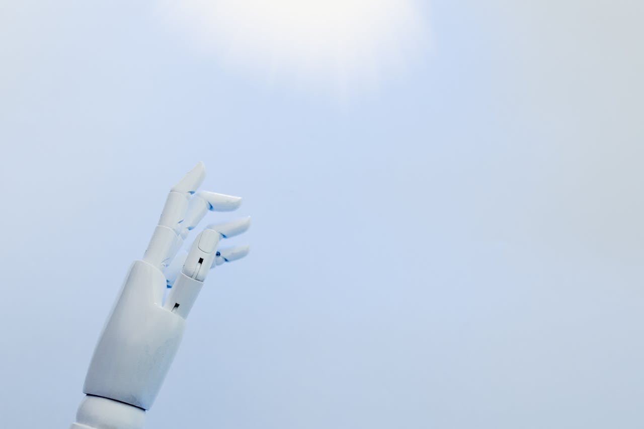 services-04 A robotic hand reaching towards a bright light on a white background symbolizing innovation.
